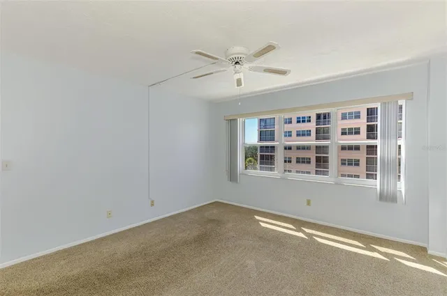 an empty room with chandelier fan and windows