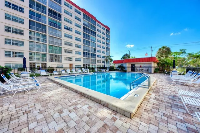 a front view of a building with garden and trees