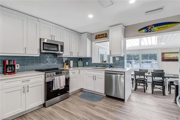 a kitchen with stainless steel appliances granite countertop a stove top oven a sink dishwasher and a microwave oven on the wooden floor