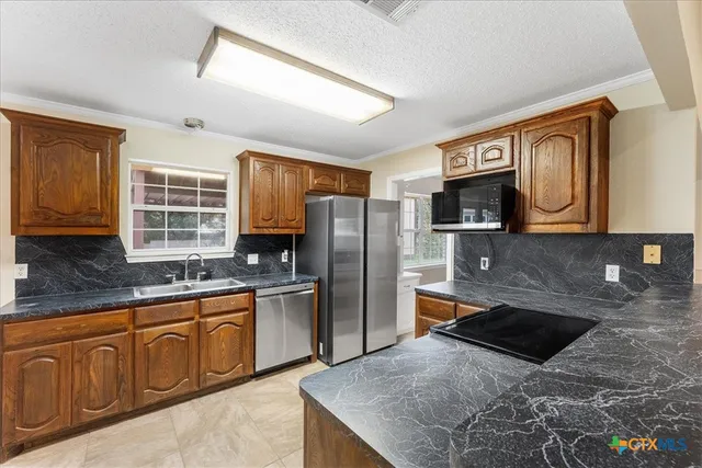 a kitchen with stainless steel appliances granite countertop a sink stove microwave and refrigerator