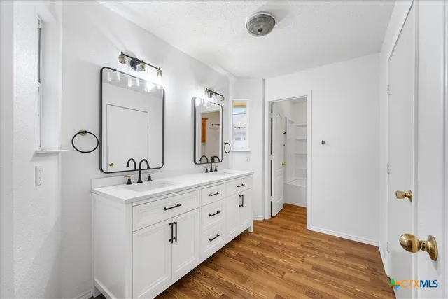 a spacious bathroom with a double vanity sink a mirror and shower