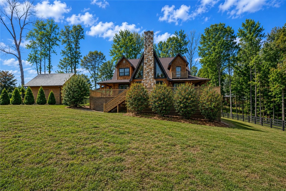 414 Devon Way Anderson, SC 29621 - Photo 36 of 50 A striking stone chimney anchors this rustic lodge, complemented by verdant landscaping and mature trees.