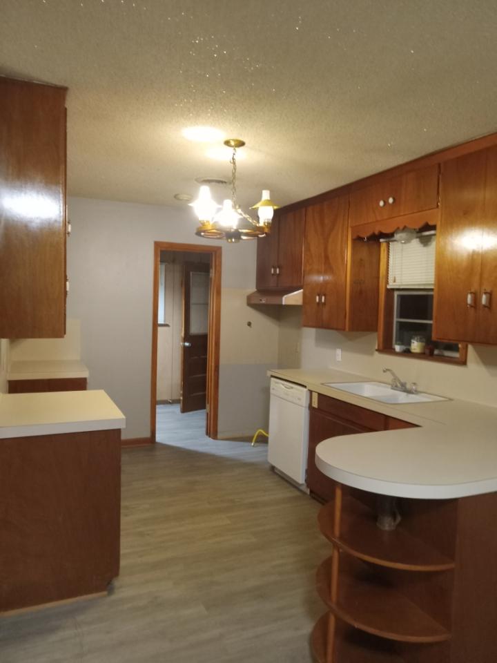 709 West 11th Street Elgin, TX 78621 - Photo 10 of 12 Kitchen featuring wood finish cabinetry, light countertops, suspended lighting, light wood-style floors, and a textured ceiling