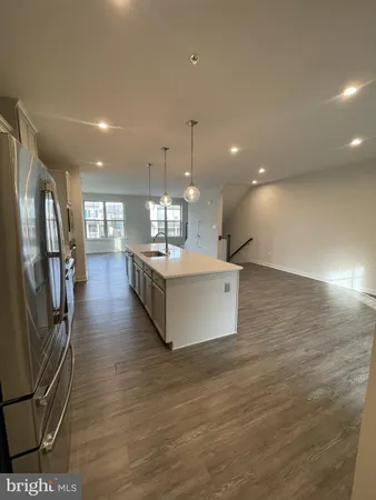 a large room with kitchen island a large counter top space a sink stainless steel appliances and cabinets