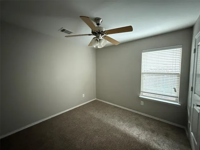 an empty room with a window and a fan