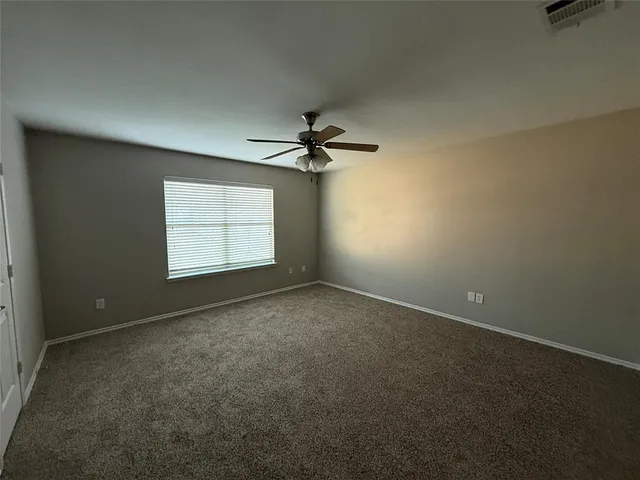 an empty room with a ceiling fan and window