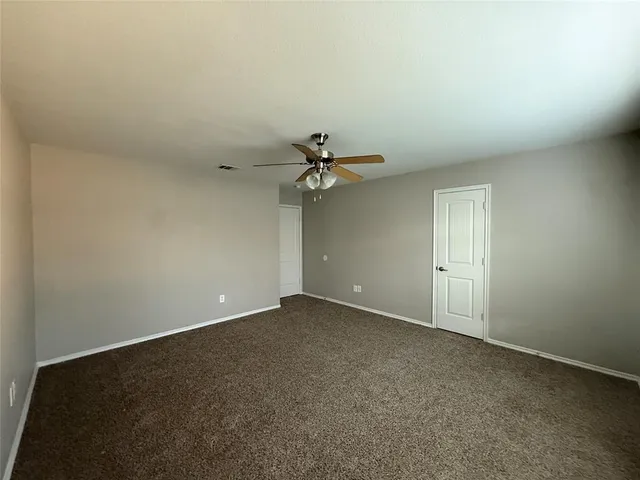 an empty room with a chandelier fan and windows