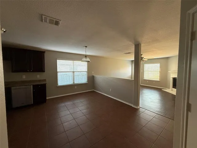 a view of an empty room with a kitchen and a window