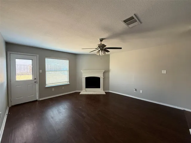 an empty room with wooden floor a fireplace and windows
