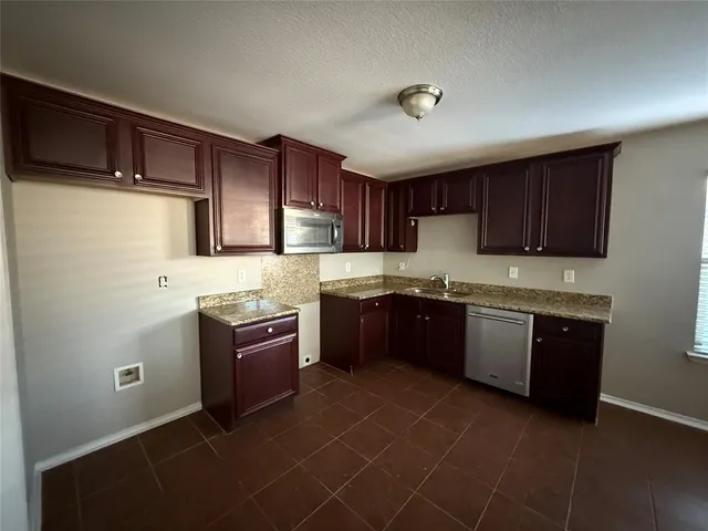 a kitchen with stainless steel appliances granite countertop a stove a sink dishwasher and a refrigerator