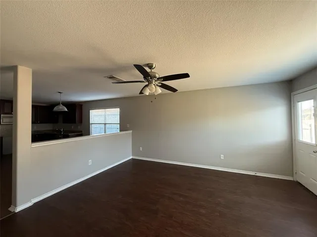 an empty room with wooden floor fan and windows