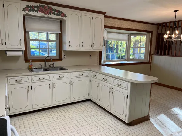 a kitchen with granite countertop white cabinets white appliances wooden floor and a window