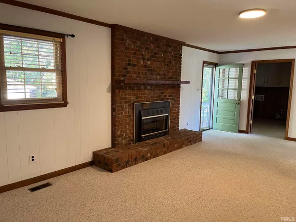 a view of an empty room with a fireplace and a window