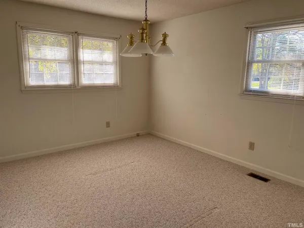 an empty room with a windows and chandelier