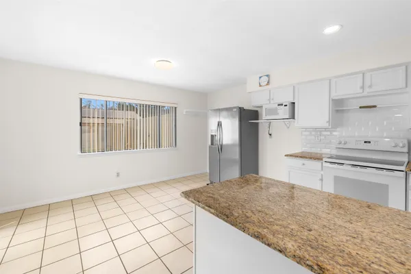 a kitchen with granite countertop a sink cabinets stainless steel appliances and a window
