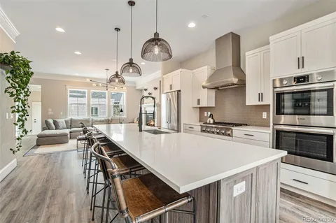 a kitchen with stainless steel appliances a stove a table a sink and a refrigerator