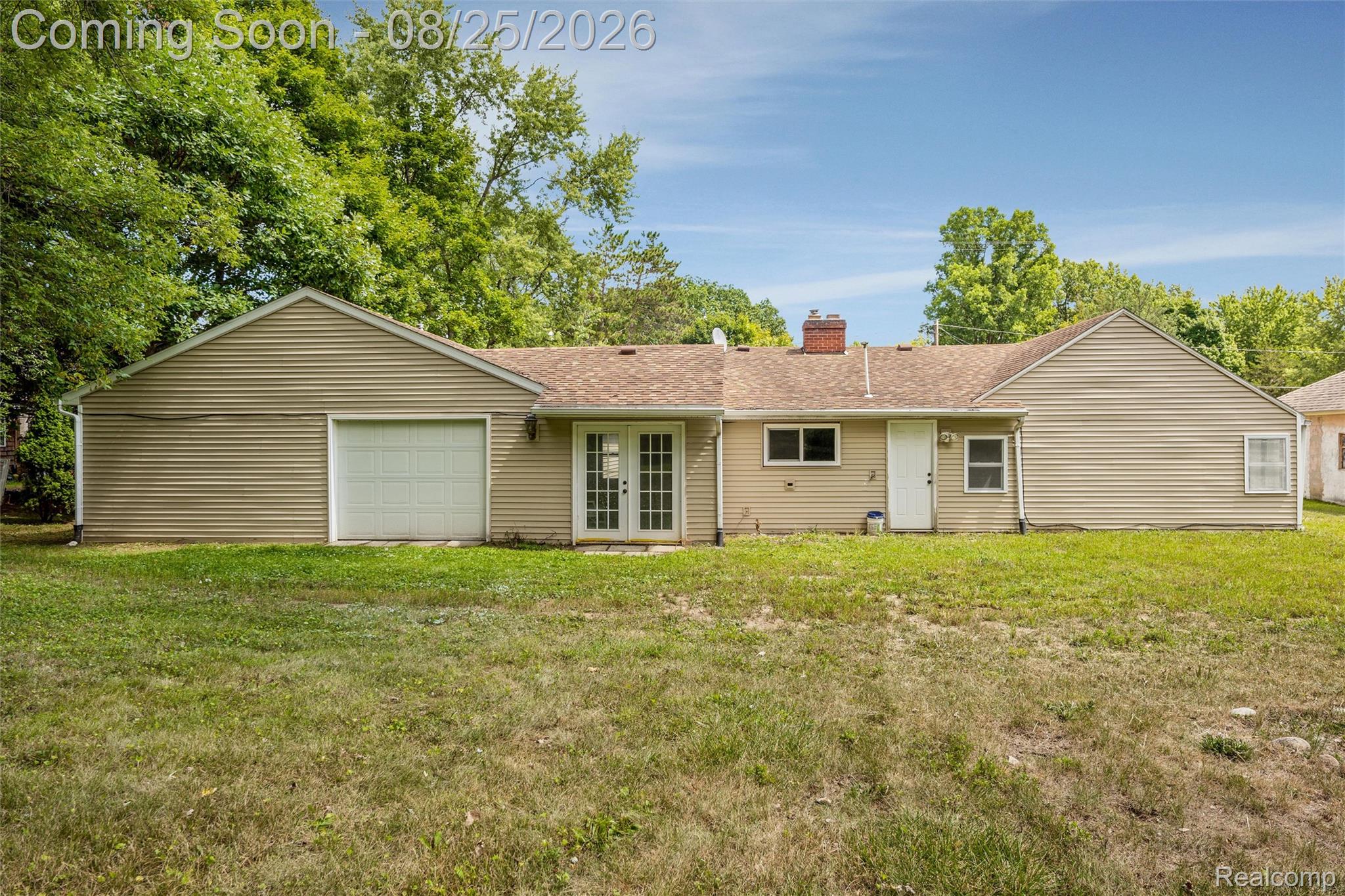 1156 Rinn Street Burton, MI 48509 - Photo 22 of 25 Rear exterior with neutral-toned siding, attached garage, and a central French door entry