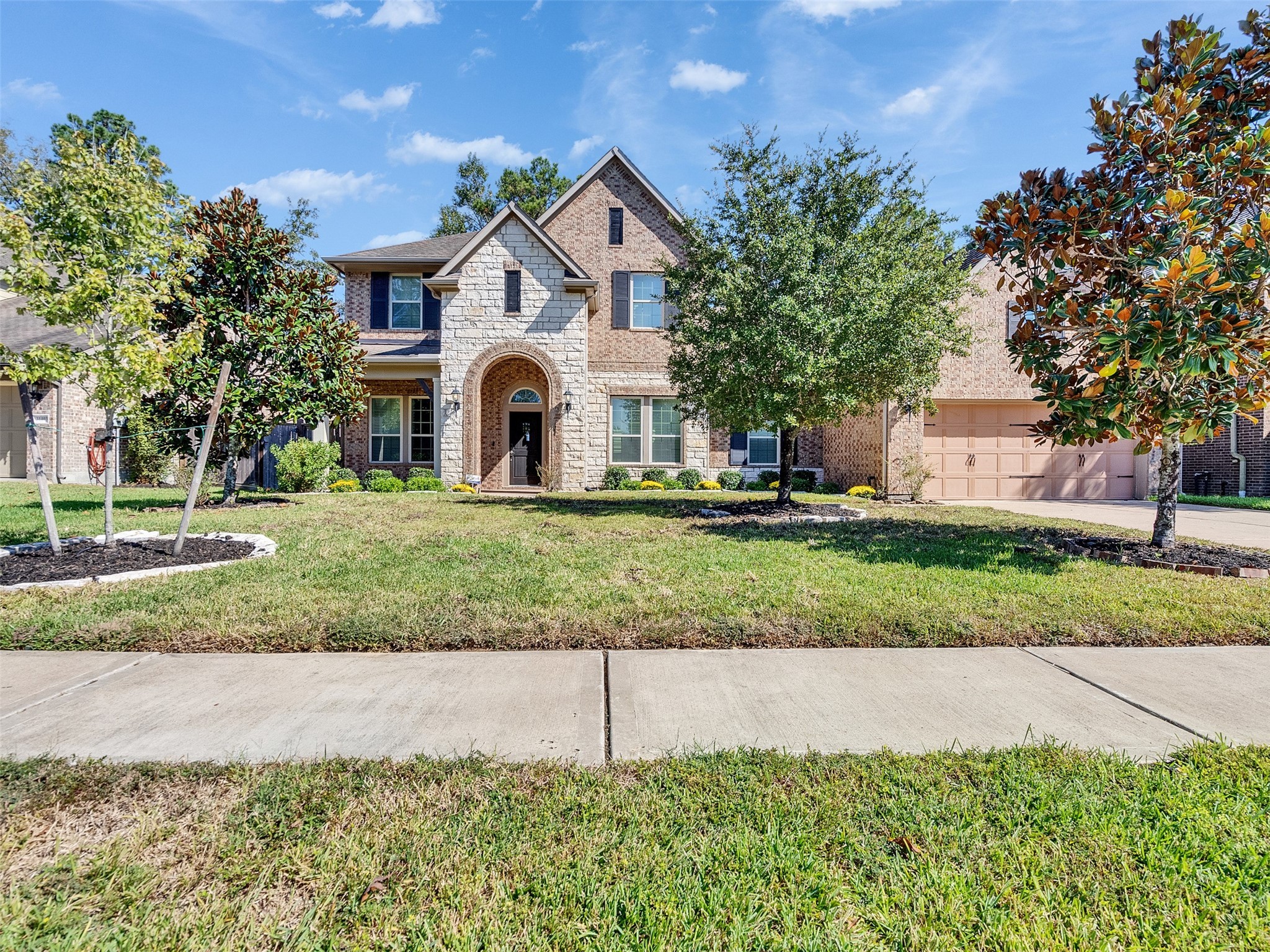 This charming two-story brick home features a welcoming arched entryway, a spacious driveway, and a well-maintained front yard with landscaped greenery. Situated in a leafy neighborhood, it offers a serene and inviting ambiance.