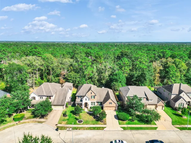 an aerial view of residential houses with outdoor space and trees all around