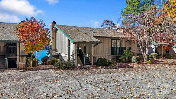 a view of a house with a small yard and a large tree