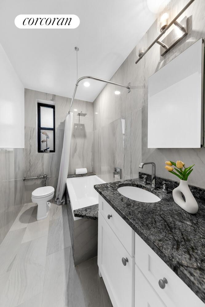 225 East 74th Street, Unit 5A Manhattan, NY 10021 - Photo 6 of 7 a bathroom with a granite countertop sink a toilet and a mirror