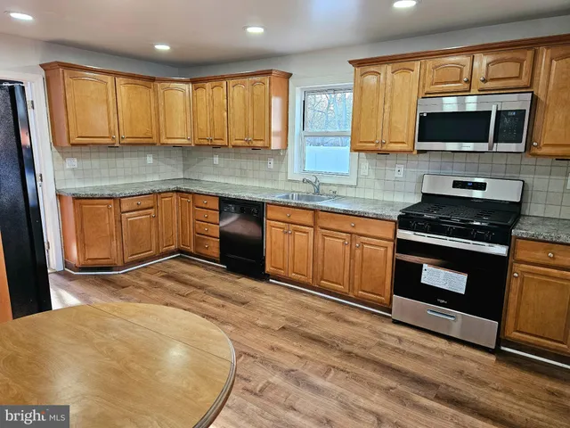 a kitchen with stainless steel appliances granite countertop wooden cabinets a stove top oven a sink and dishwasher