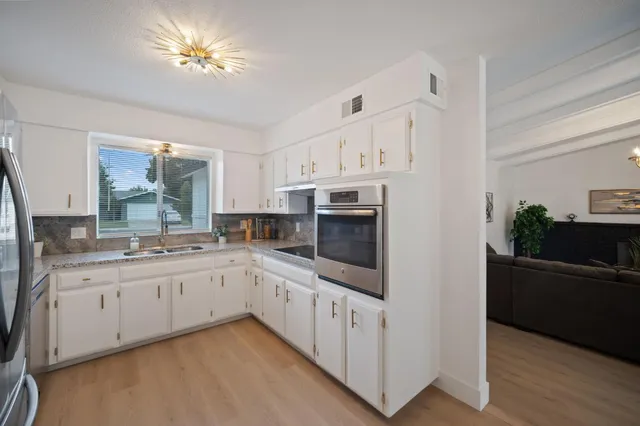 a kitchen with stainless steel appliances a sink a stove a refrigerator cabinets and a window