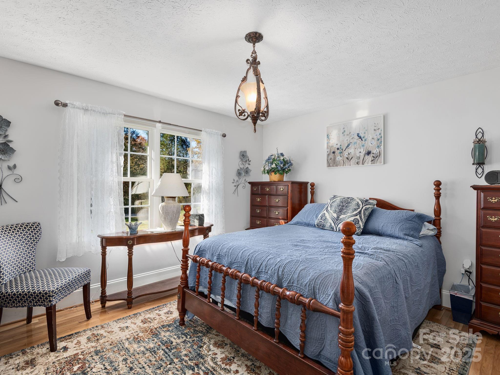 201 Sean Way Hendersonville, NC 28792 - Photo 11 of 24 a bedroom with a bed a chandelier and a dresser