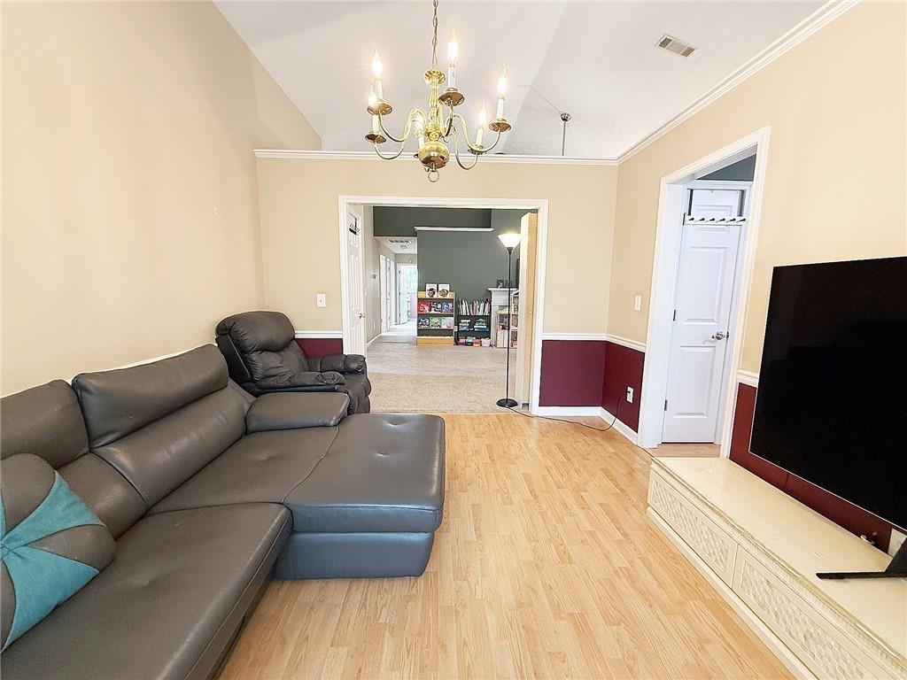 69 Morning Top Court Suwanee, GA 30024 - Photo 8 of 34 a living room with furniture a chandelier and a flat screen tv