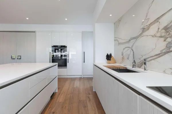 a kitchen with a sink and white cabinets with wooden floor