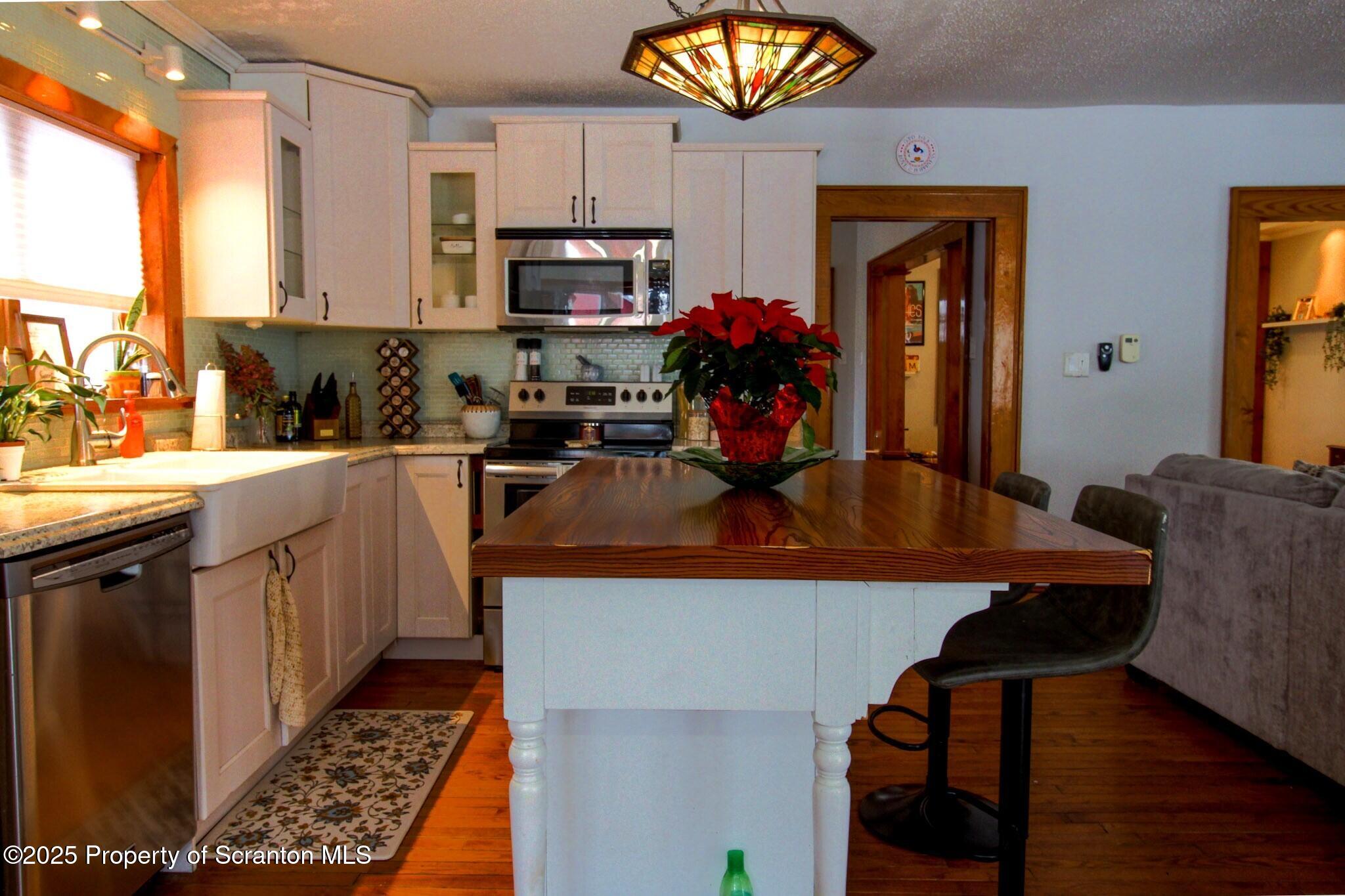 316 Bridge Street Blakely, PA 18452 - Photo 13 of 39 a kitchen with stainless steel appliances granite countertop a sink a stove top oven a chimney and a dining table