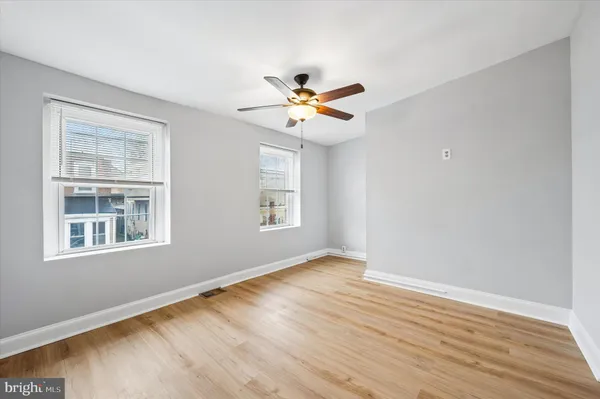 a view of an empty room with window and wooden floor