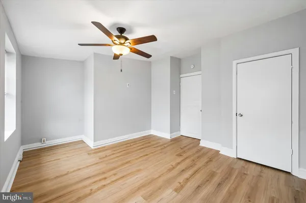a view of empty room with wooden floor and ceiling fan