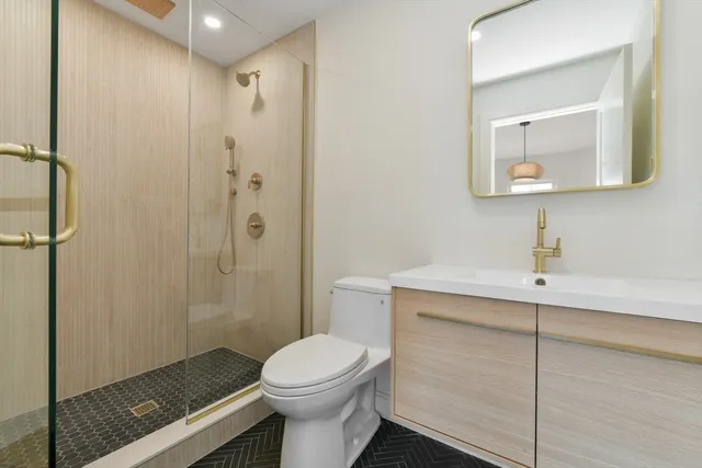 a bathroom with a toilet a sink a shower and mirror