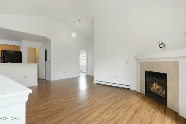 a view of an empty room with wooden floor and a fireplace