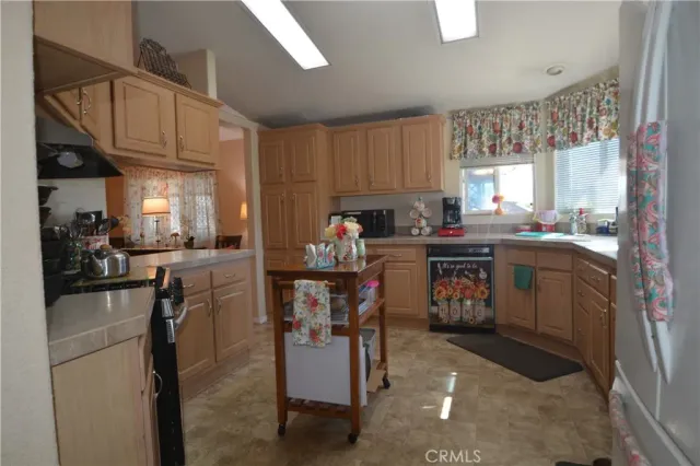 a kitchen with stainless steel appliances granite countertop a sink a stove a refrigerator cabinets and a dining table