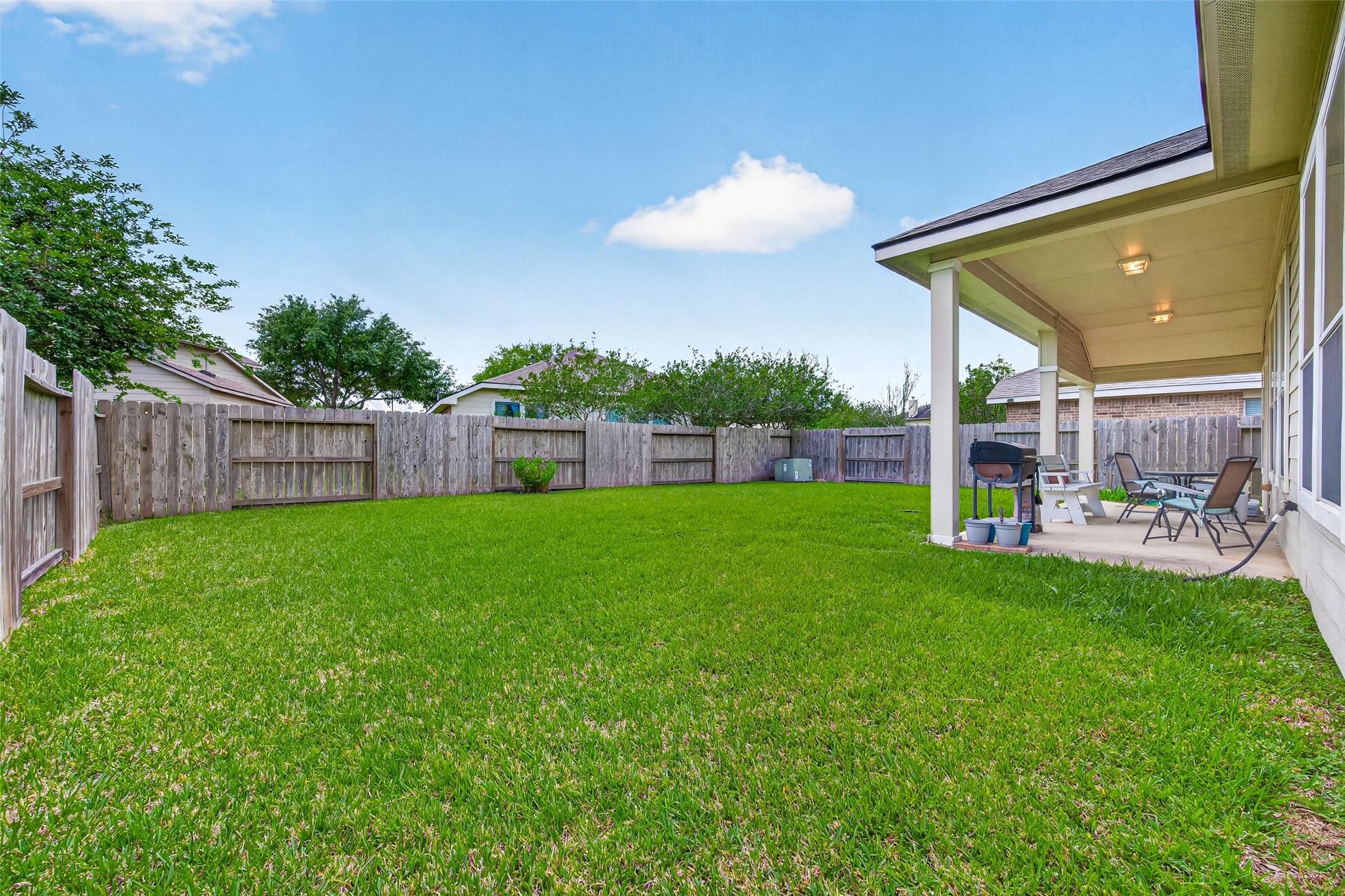 8622 Henrico Lane Rosenberg, TX 77469 - Photo 19 of 20 Spacious backyard with a well-maintained lawn, a wooden fence for privacy, and a covered patio area ideal for outdoor relaxation and entertaining.