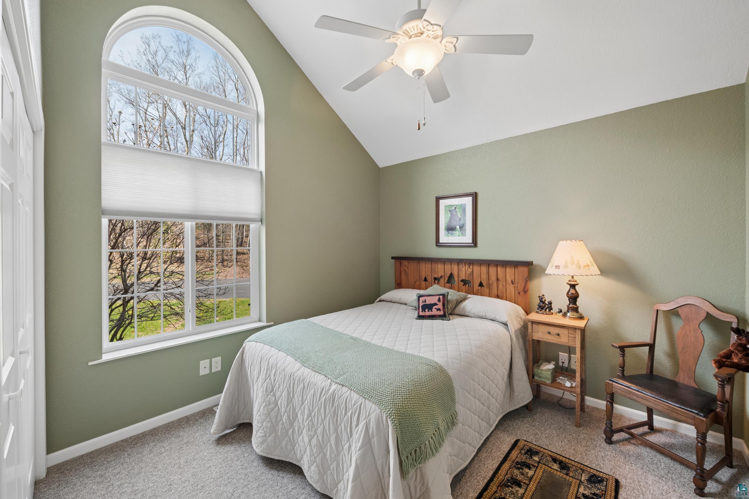 34590 Bay View Road, Unit 801 Bayfield, WI 54814 - Photo 16 of 36 Room featuring a large arched window with a double-pane design, vaulted ceiling, ceiling fan with integrated lighting, textured wall finish, and neutral carpet flooring