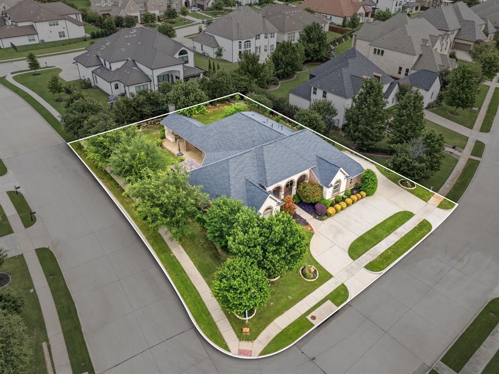 7013 Handel Colleyville, TX 76034 - Photo 6 of 37 Expansive corner lot residence featuring a dark-toned hip roof, a light-colored brick facade, and a curved concrete driveway