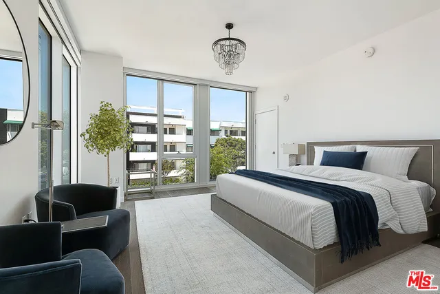 a spacious bedroom with a bed a couch and a large window