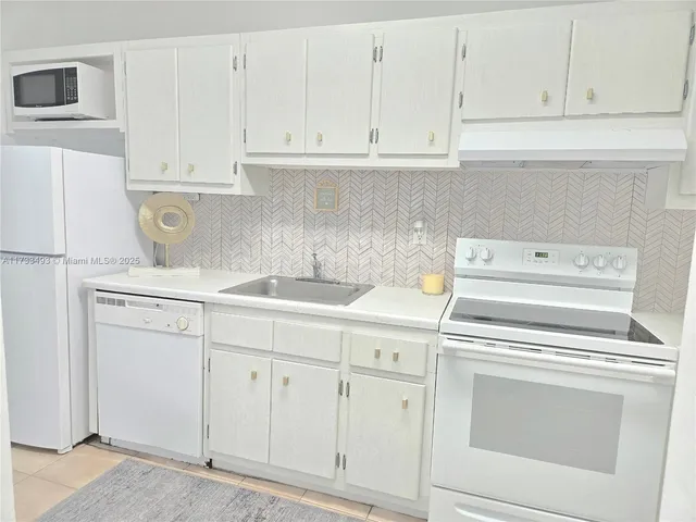 a kitchen with white cabinets and white appliances