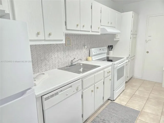 a kitchen with white cabinets and sink