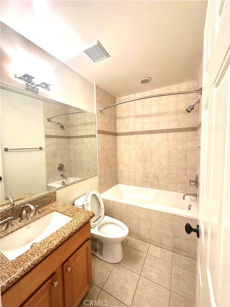 9356 19th Street, Unit A Rancho Cucamonga, CA 91701 - Photo 12 of 23 a bathroom with a granite countertop sink a toilet a mirror and bathtub