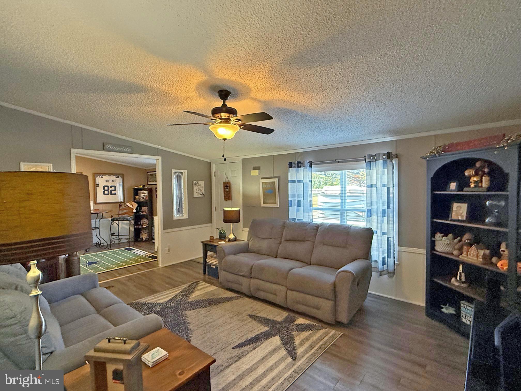 27137 Clipper Road, Unit M55 Millsboro, DE 19966 - Photo 5 of 48 a living room with furniture and a flat screen tv with wooden floor