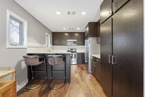 a kitchen with granite countertop a refrigerator and a stove top oven