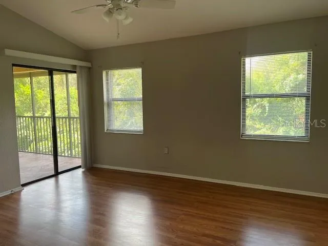 a view of an empty room with wooden floor and a window
