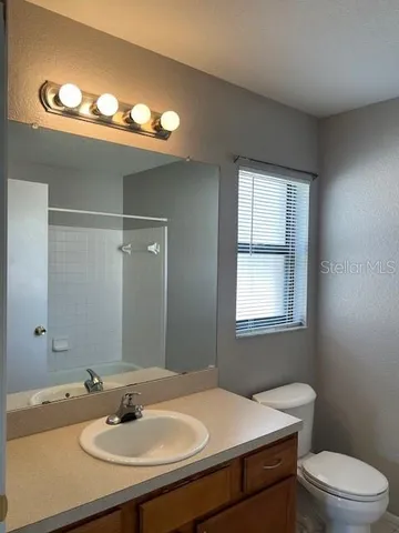 a bathroom with a sink a toilet a mirror and a window