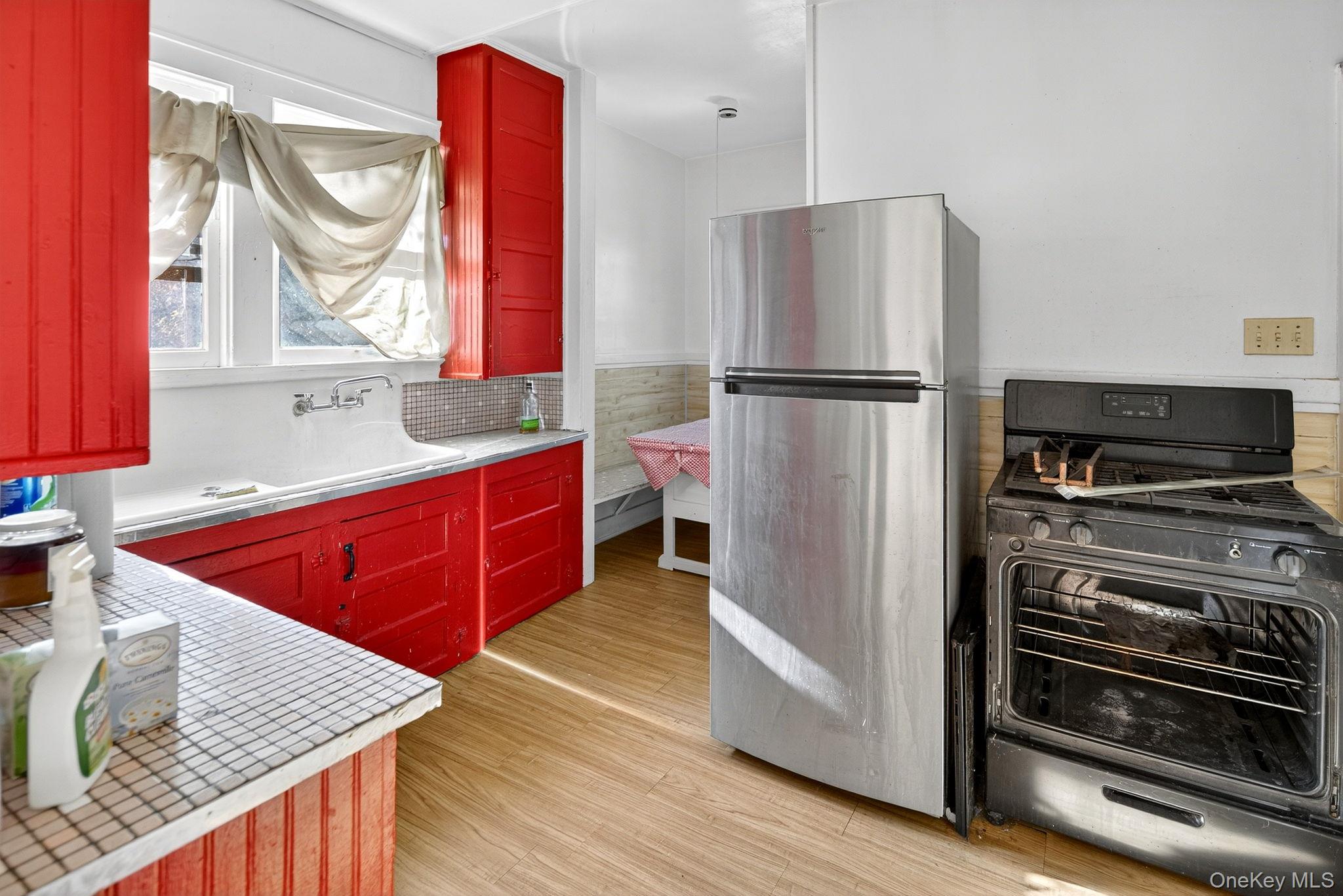 964 State Street Schenectady, NY 12307 - Photo 11 of 24 Kitchen featuring freestanding refrigerator, stove, red cabinetry, light wood-style flooring, and decorative backsplash