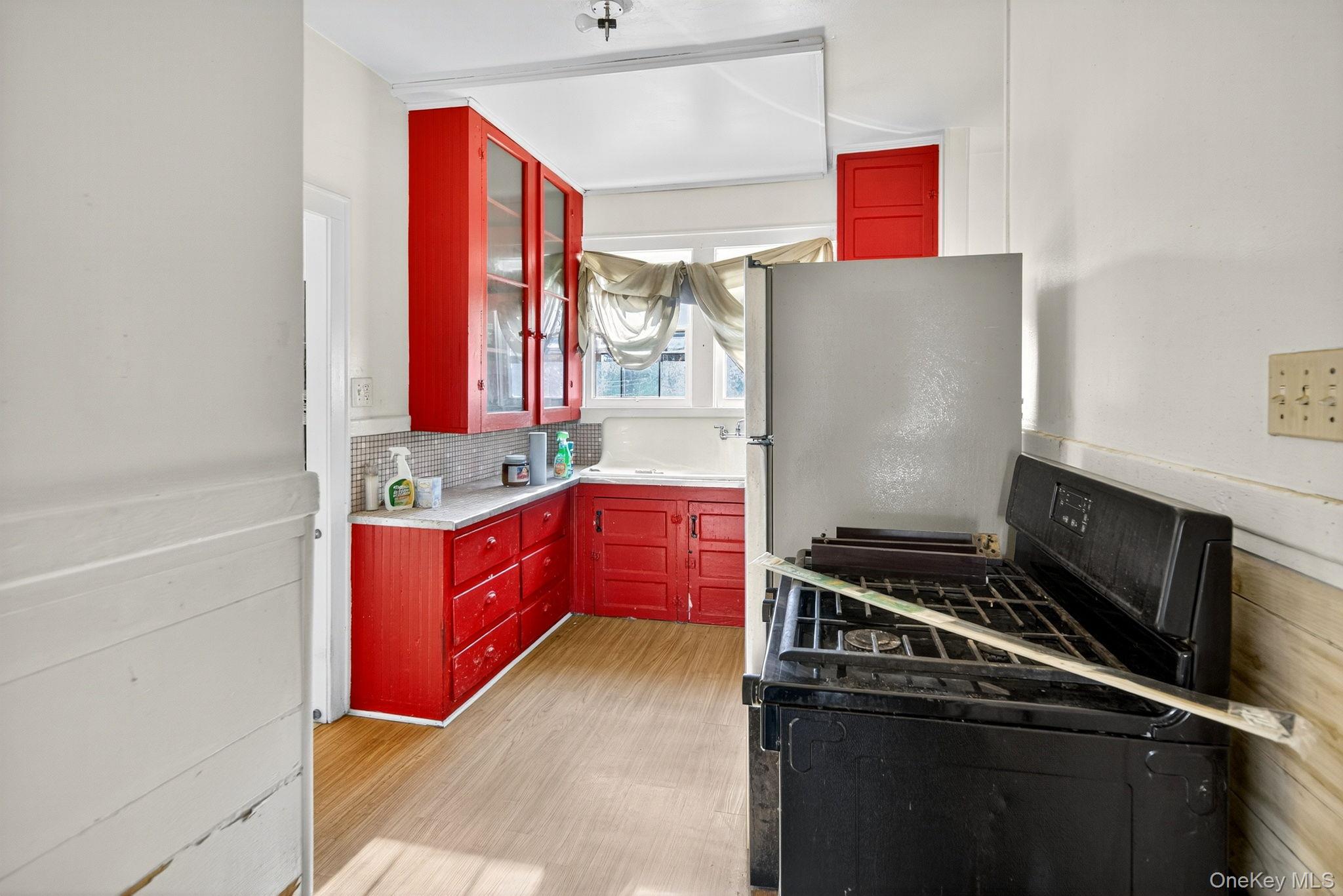 964 State Street Schenectady, NY 12307 - Photo 13 of 24 Kitchen with black range with gas stovetop, light countertops, red cabinets, light wood-type flooring, and glass insert cabinets