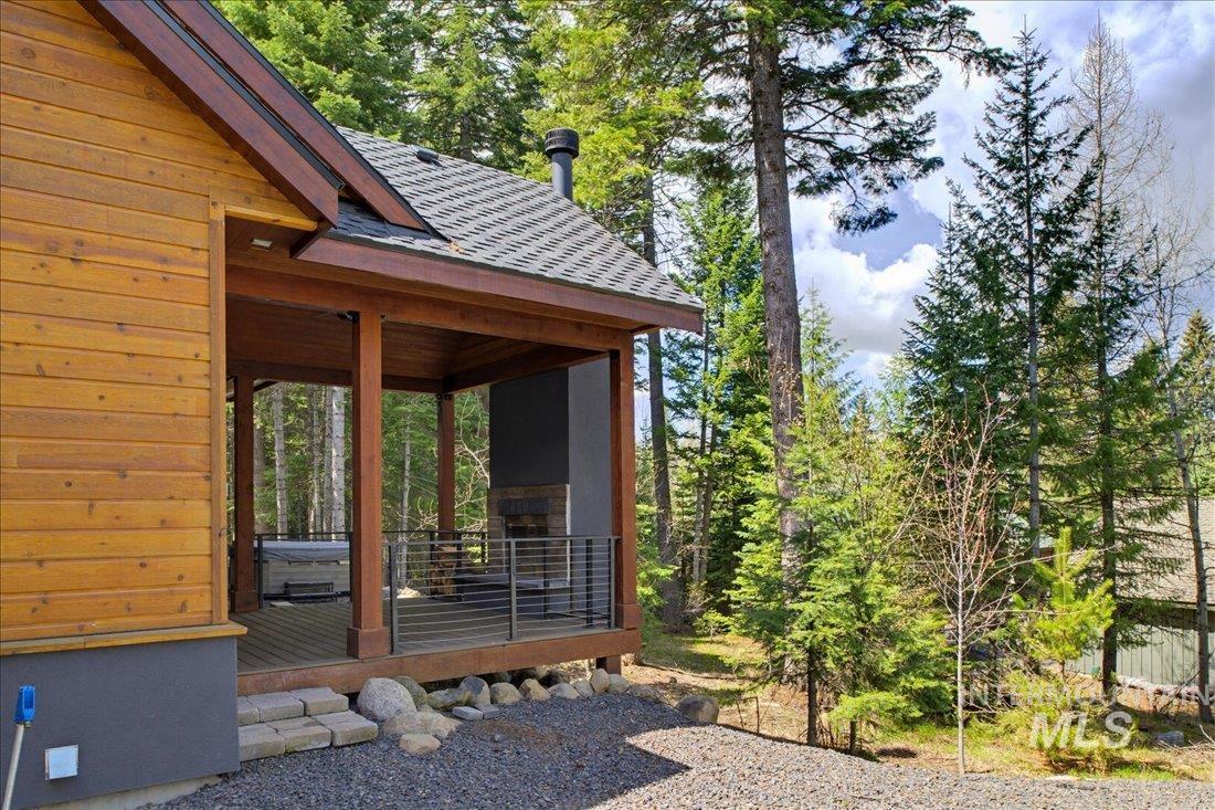 1051 Bitterroot Drive McCall, ID 83638 - Photo 22 of 26 Covered outdoor patio featuring wood siding, built-in fireplace, and a hot tub
